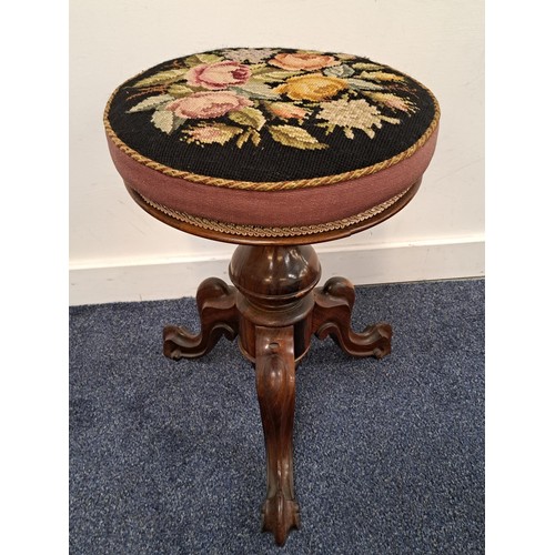 VICTORIAN ROSEWOOD ADJUSTABLE PIANO STOOL
with a circular needlework seat decorated with flowers, on a turned column and tripod base, 50.5cm high