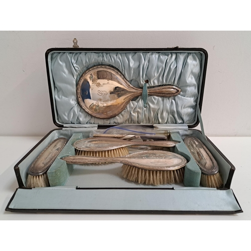 GEORGE V SILVER DRESSING TABLE SET
comprising a hand mirror, comb, two large brushes and two other brushes, all with a monogrammed G, in a fitted satin lined case, Birmingham 1924 by David Moss & Co