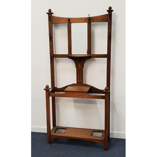 ARTS AND CRAFTS OAK HALL STAND
with a shaped top rail above a central bevelled mirror with a shelf below, with an arrangement of eight clothes hooks above a central lower inlaid tulip with a lift up lid glove box below flanked by two open stick stands with a shelf below, 200cm x 94cm 33cm