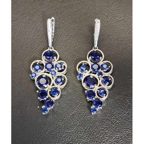 108 - TWO ORNATE SILVER PENDANTS
both set with diamonds to the suspension loop and faceted blue glass to t... 