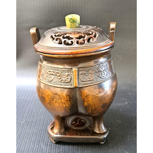 252 - CHINESE BRONZE CENSER 
with a bulbous squat body and panel of relief decoration, raised on three sha... 