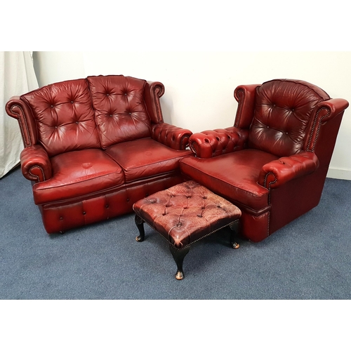 OX BLOOD CHESTERFIELD SOFA
with two seats and loose button back and seat cushions, with scroll arms with decorative metal stud detail, on casters, 127cm wide, together with a matching armchair and button back footstool (3)