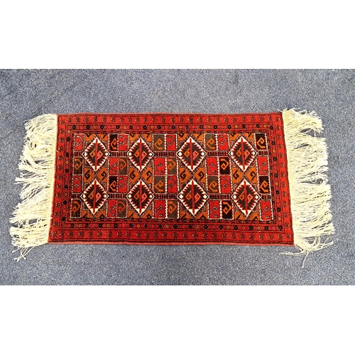 403 - A WOOLEN TURKAMEN PRAYER MAT 
on red and orange ground with geometric motif and fringing, 100x 58cm