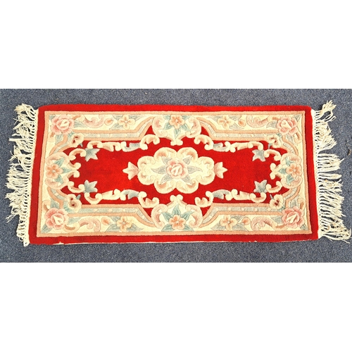 623 - WOOLEN AUBOSSON STYLE RUG
on red ground with fringe, 120 x 62cm