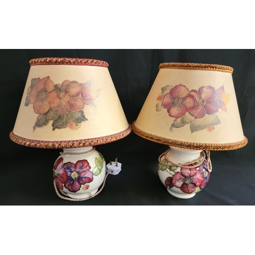 300 - A PAIR OF MOORCROFT 'CLEMATIS' PATTERNED LAMP BASES 
the cream ground with painted flowers of variou... 