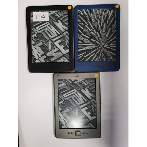 142 - THREE AMAZON KINDLE E-READERS
comprising a Basic 4 blue, serial number G092 AQ05 3405 05QU; a Basic ... 