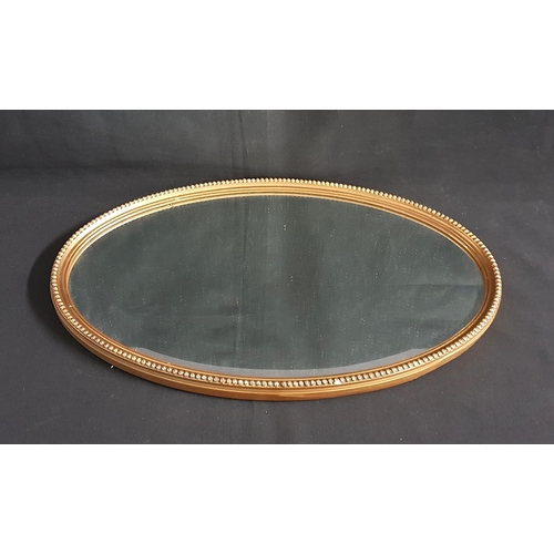 695 - OVAL GILT FRAMED WALL MIRROR
with beading decoration to frame and with bevel edge to glass, 58 x 36c... 