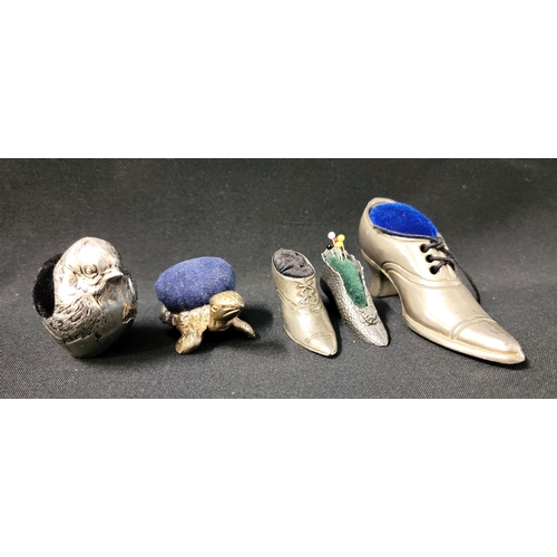 203 - FIVE WHITE METAL PIN CUSHIONS
comprising three shoes, the largest 10.5cm long; a tortoise and a chic... 