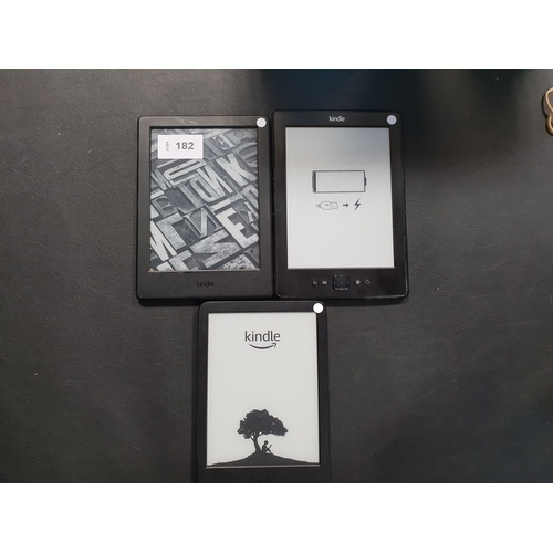 182 - THREE AMAZON KINDLE E-READERS
comprising a Basic 4, serial number G092 AP05 4037 061K; a Basic 2, se... 