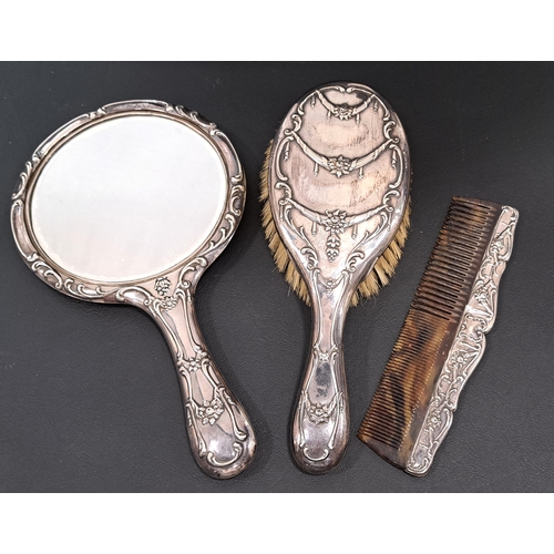 166 - GEORGE V SILVER BACKED DRESSING TABLE SET 
comprising a brush, a mirror and a comb, all with scroll ... 