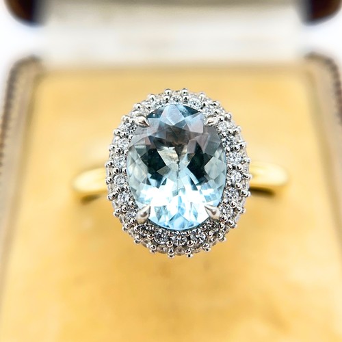 26 - An Aquamarine and Diamond Halo Ring

The 18ct yellow gold ring is set with a good colour oval-cut aq... 