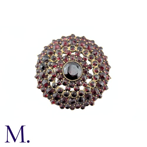 33 - A Bohemian Garnet Brooch in yellow metal, the central round cut garnet surrounded by five rows of ro... 