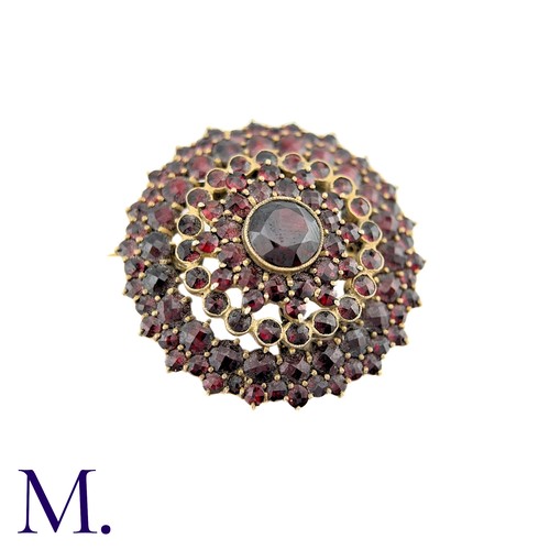 33 - A Bohemian Garnet Brooch in yellow metal, the central round cut garnet surrounded by five rows of ro... 