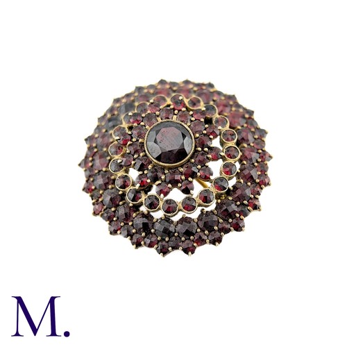 33 - A Bohemian Garnet Brooch in yellow metal, the central round cut garnet surrounded by five rows of ro... 