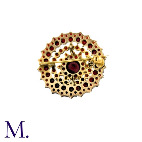 33 - A Bohemian Garnet Brooch in yellow metal, the central round cut garnet surrounded by five rows of ro... 