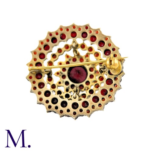 33 - A Bohemian Garnet Brooch in yellow metal, the central round cut garnet surrounded by five rows of ro... 