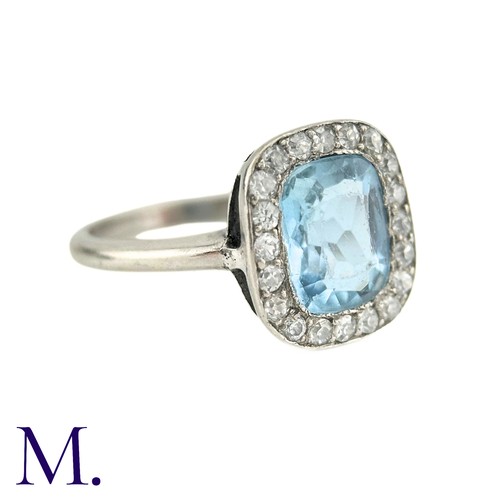 58 - An Aquamarine And Diamond Cluster Ring in white gold, the principal cushion cut aquamarine surrounde... 