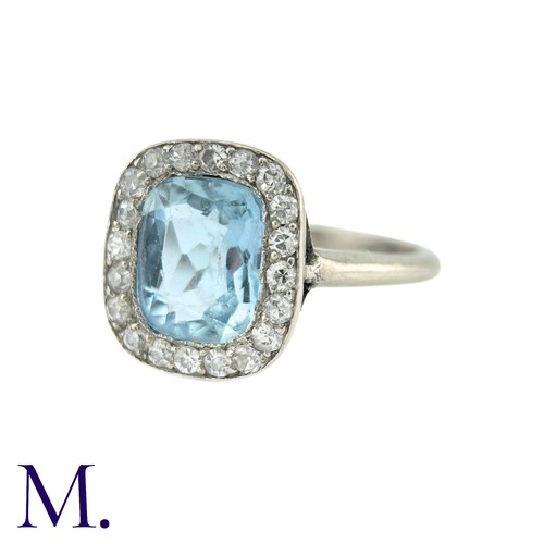 58 - An Aquamarine And Diamond Cluster Ring in white gold, the principal cushion cut aquamarine surrounde... 