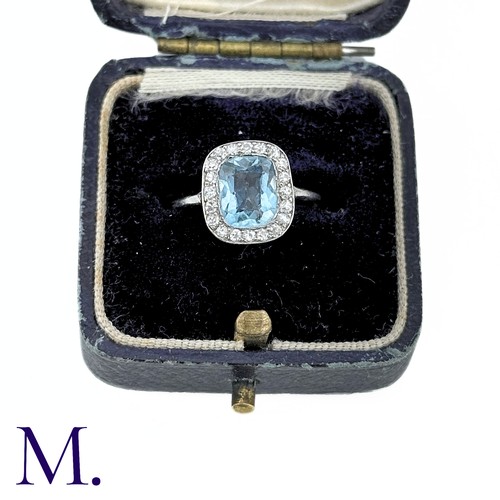 58 - An Aquamarine And Diamond Cluster Ring in white gold, the principal cushion cut aquamarine surrounde... 