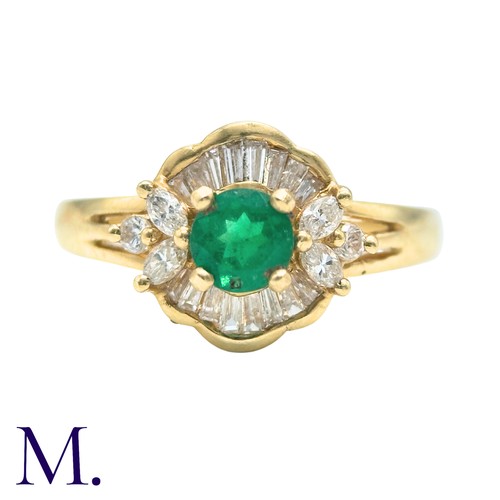 32 - An Emerald And Diamond Cluster Ring in 18k yellow gold, set with a principal round cut emerald accen... 