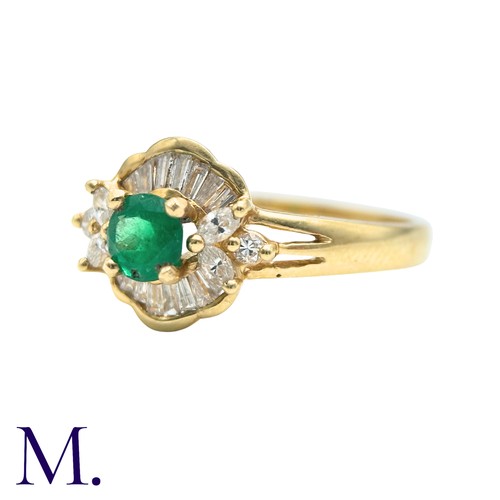 32 - An Emerald And Diamond Cluster Ring in 18k yellow gold, set with a principal round cut emerald accen... 