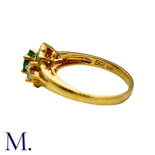 32 - An Emerald And Diamond Cluster Ring in 18k yellow gold, set with a principal round cut emerald accen... 