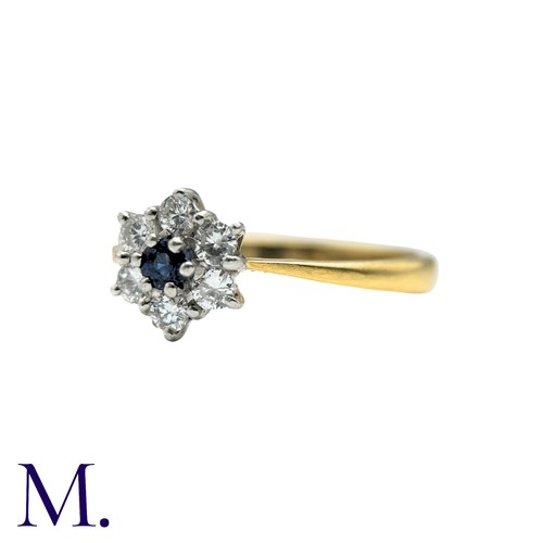 57 - A Sapphire And Diamond Cluster Ring in 18k yellow gold, set with a round cut sapphire within a round... 