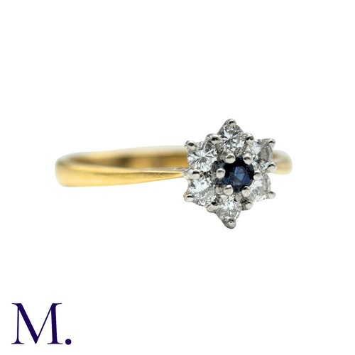 57 - A Sapphire And Diamond Cluster Ring in 18k yellow gold, set with a round cut sapphire within a round... 