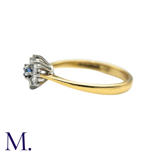 57 - A Sapphire And Diamond Cluster Ring in 18k yellow gold, set with a round cut sapphire within a round... 