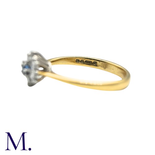 57 - A Sapphire And Diamond Cluster Ring in 18k yellow gold, set with a round cut sapphire within a round... 