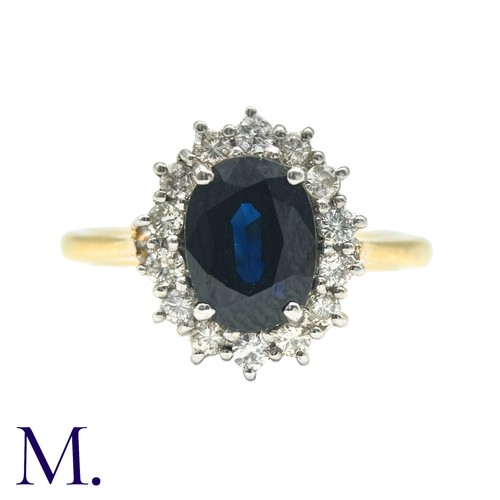 30 - A Sapphire And Diamond Cluster Ring in 18k yellow gold, set with an oval cut sapphire of approximate... 