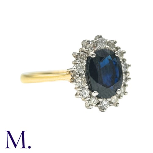 30 - A Sapphire And Diamond Cluster Ring in 18k yellow gold, set with an oval cut sapphire of approximate... 