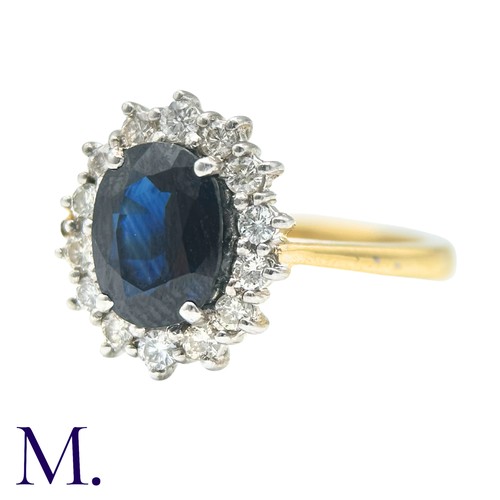 30 - A Sapphire And Diamond Cluster Ring in 18k yellow gold, set with an oval cut sapphire of approximate... 