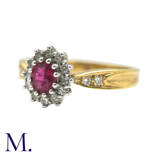 29 - A Ruby And Diamond Cluster Ring in 18k yellow gold, set with an oval cut ruby set within a round cut... 