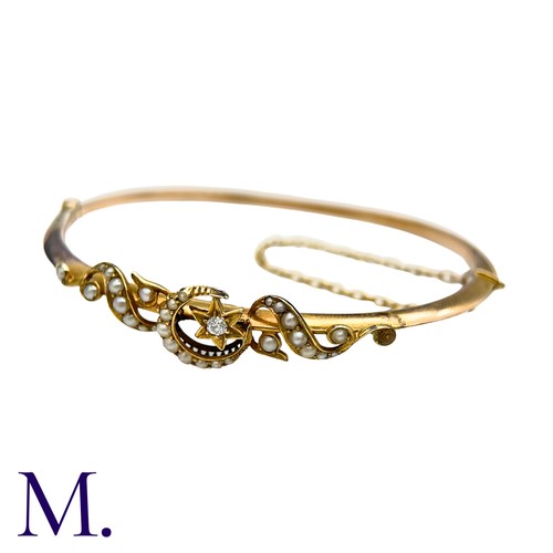 18 - A Pearl And Diamond Bangle  in yellow gold, with pearl set scrolling motifs, a pearl set crescent an... 