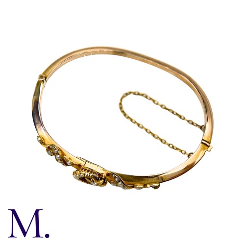 18 - A Pearl And Diamond Bangle  in yellow gold, with pearl set scrolling motifs, a pearl set crescent an... 