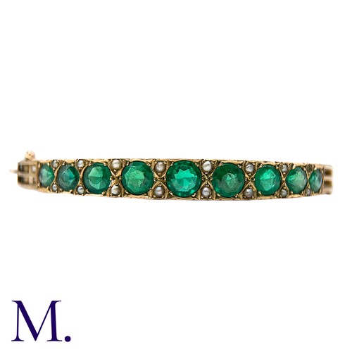 58 - A Green Paste And Pearl Bangle in yellow gold, set with a row of graduated round cut green paste sto... 