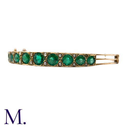 58 - A Green Paste And Pearl Bangle in yellow gold, set with a row of graduated round cut green paste sto... 