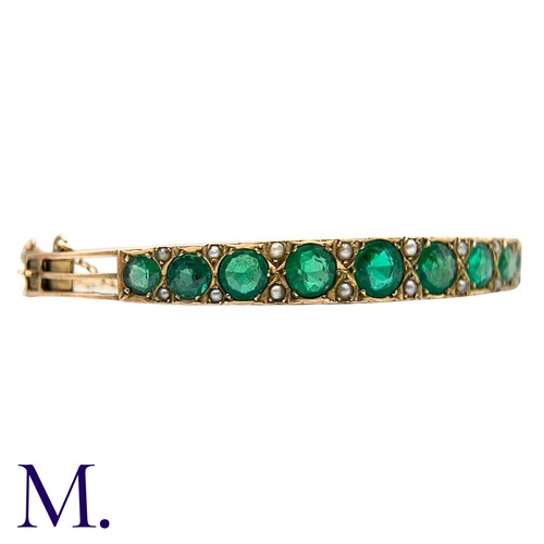 58 - A Green Paste And Pearl Bangle in yellow gold, set with a row of graduated round cut green paste sto... 