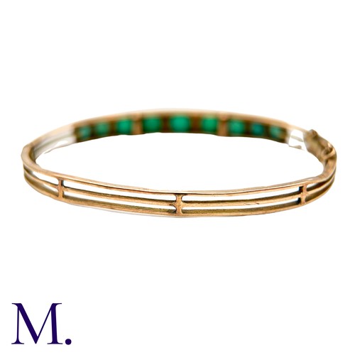 58 - A Green Paste And Pearl Bangle in yellow gold, set with a row of graduated round cut green paste sto... 