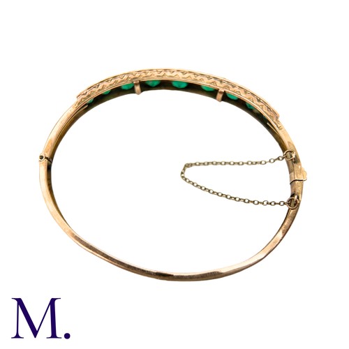 58 - A Green Paste And Pearl Bangle in yellow gold, set with a row of graduated round cut green paste sto... 
