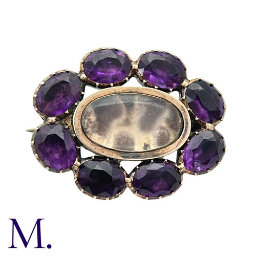 27 - An Amethyst And Glass Brooch in yellow gold, comprising a cluster of oval cut amethyst around a glas... 