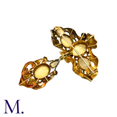 42 - A Citrine And Emerald Brooch in yellow gold, the ornate scrolling body set with oval cut citrine and... 