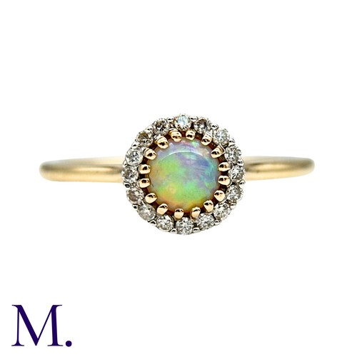 22 - An Opal And Diamond Cluster Ring in 9k yellow gold, set with a cabochon within a round cut diamond b... 