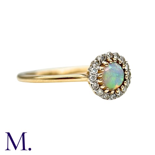 22 - An Opal And Diamond Cluster Ring in 9k yellow gold, set with a cabochon within a round cut diamond b... 