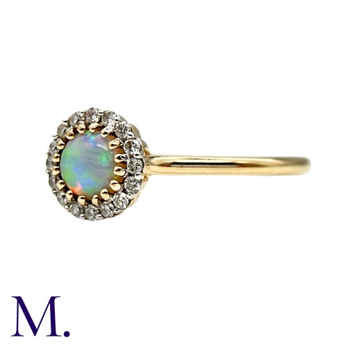 22 - An Opal And Diamond Cluster Ring in 9k yellow gold, set with a cabochon within a round cut diamond b... 