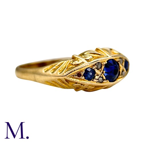 14 - A Sapphire And Diamond Ring in 18k yellow gold, Seth with three round cut blue sapphire punctuated b... 