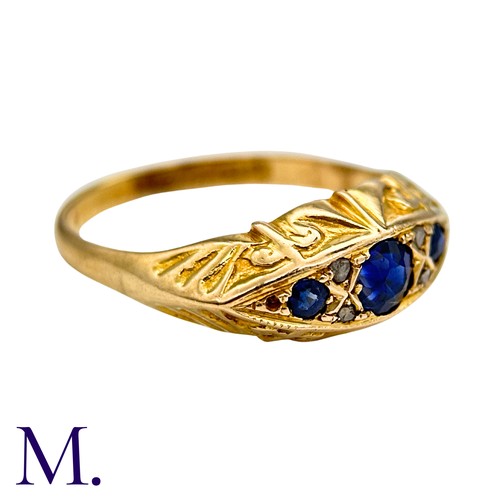 14 - A Sapphire And Diamond Ring in 18k yellow gold, Seth with three round cut blue sapphire punctuated b... 