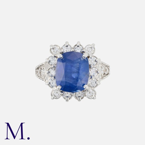 113 - A Sapphire And Diamond Cluster Ring in 18k white gold, set with a principal cushion cut sapphire of ... 