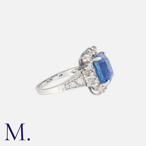 113 - A Sapphire And Diamond Cluster Ring in 18k white gold, set with a principal cushion cut sapphire of ... 